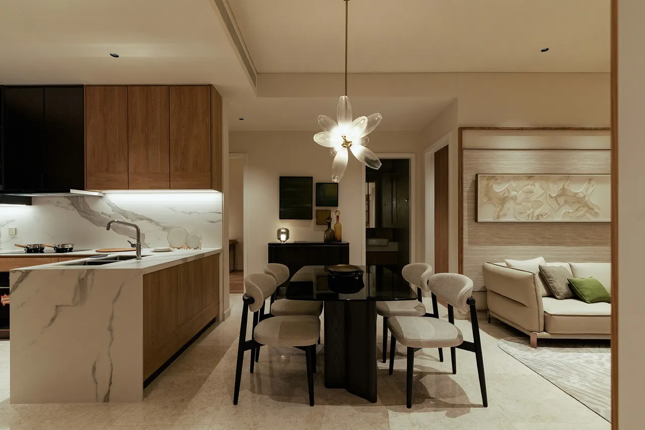 Dining area with sculptural pendant light beside the open kitchen — show unit