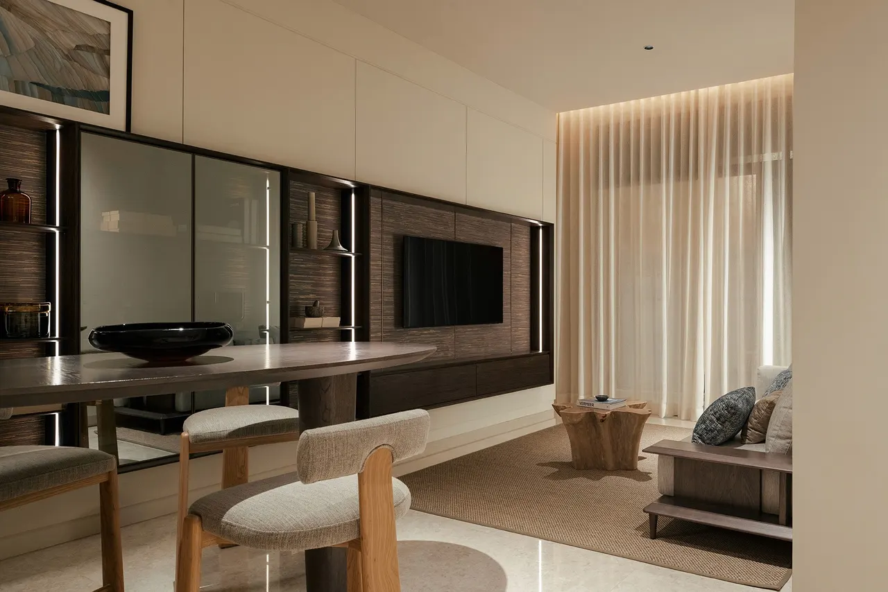 Living area with feature media wall and sheer-draped seafront windows — show unit